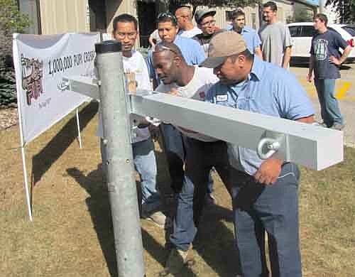 Geotek employees sign their names to the millionth crossarm last Wednesday, Sept. 11 to celebrate the fact that the company has manufactured 1 million fiberglass crossarms for electric utility poles since 1990.