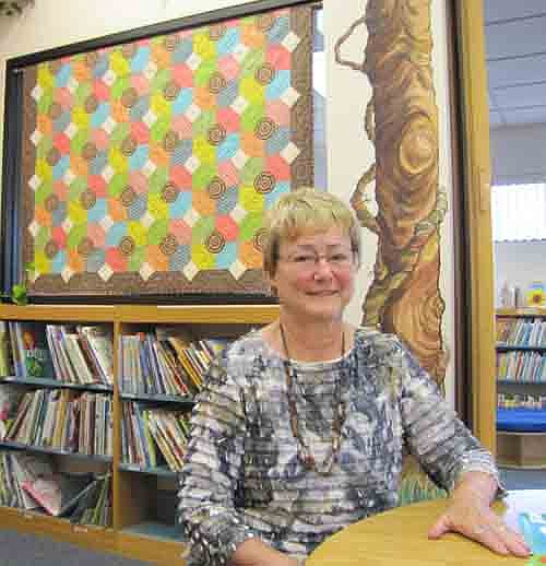 Ginny Hanson of Stewartville learned how to quilt 18 years ago when she took a community education applique quilting class in Rochester. She has given away many of her quilts, including the one currently hanging on the wall at the children's section of the Stewartville Public Library.  A closeup of the quilt, at left, reveals stacks of books and a carousel of books seen from above.