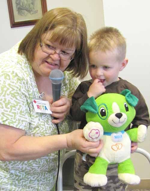 The Stewartville Care Center celebrated National Bring Your Teddy Bear to Work Day by inviting children in Nichol O'Neill's day care to bring teddy bears and other stuffed animals to the Care Center last week. Here, Rita Christian of the Care Center staff helps Liam O'Neill, 3, display a stuffed animal.
