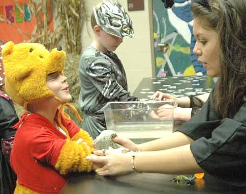 Grace Menchaca, a junior and a member of the Stewartville High School Key Club, gives Aaron Anderson, 6, of Stewartville, dressed as Winnie the Pooh, a tattoo at the Kiwanis and Key Clubs' Trick-or-Treat Night at Stewartville High School on Saturday, Nov. 2.