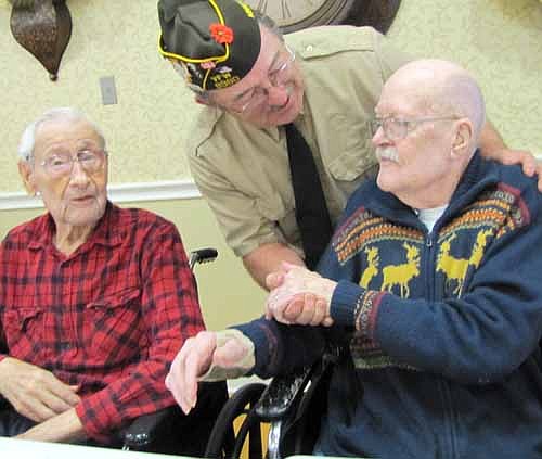 Roger Peterson, commander of the Stewartville VFW Post 8980, standing, greets veteran Harry Geerdes, right, on Veterans Day.