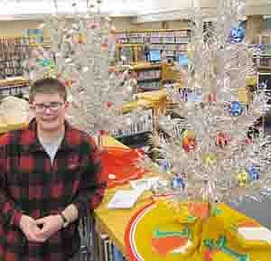 Sam Edge, a senior at Stewartville High School and a page at the Stewartville Public Library, has brought three aluminum Christmas trees to the library. "It's something whimsical and different,"&#8200;he said.