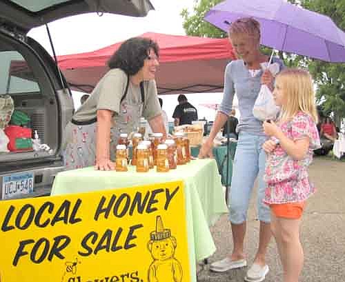 Betty Kosnopfal, left, sells B's Honey to Sharon Peterson and her granddaughter Arianna Woitas at the Farmers Market in August.