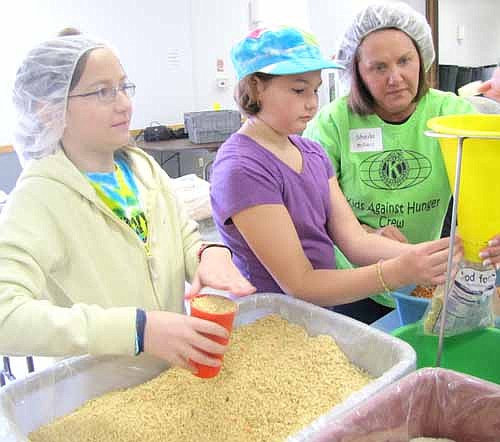 Sheila McNeill of the Stewartville Kiwanis Club, right, helps Girl Scouts Emma Thomason, center, and Kaileigh Weber at the Food for Kidz food-packing event last April.