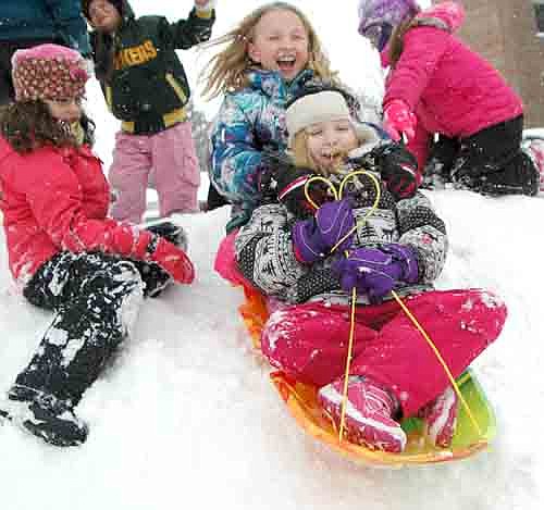 Abbi Parry, a third grader at Central Intermediate School, seated at the top of the sled, shouts for joy as she and sledding partner Arianna Woitas, another third grader, head down the hill near Central during morning recess last Thursday, Jan. 30. Emma Rowen, another third grader, left, looks on after assisting Abbi and Arianna down the hill.