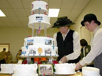 Cake designer Margaret Lex, at left, and Ardis Copple, dressed in 1800s fashions, cut the cake during January's opening sesquicentennial ceremony. 