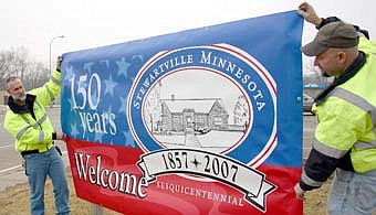 Owen Sass, left, and Sean Hale, city public works employees, hold one of two sesquicentennial banners that were on display near the entrances to the city in 2007. 
