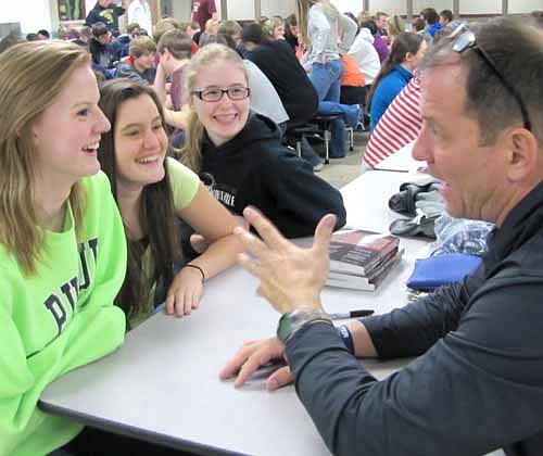 Bobby Petrocelli, a motivational speaker with an inspiring message, right, spoke to three different groups at Stewartville High School last week, sharing his gripping personal story emphasizing that forgiveness is the key to overcoming painful tragedy. After his presentation to more than 500 SHS students on Tuesday, March 4, Petrocelli met with students in the SHS cafeteria, including smiling sophomores, from left, Hannah James, Jessica Tilson and Kyanne Hilger.