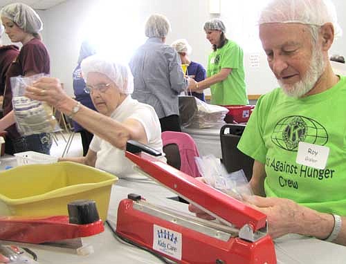 Roy Gisler of the Stewartville Kiwanis Club, in foreground at right, and his wife Carol work at the Food for Kidz food-packing event for the poor at the Stewartville Civic Center last April. This year's Food for Kidz will be held on Saturday, April 5.