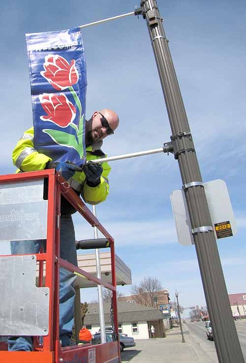 Eric Domino of the city of Stewartville's public works department places a spring/summer "Welcome to Stewartville" banner on a pole along Main Street last week.