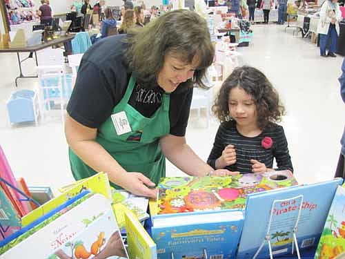 Andrea Sztajnkrycer of Rochester, who hosted the Usborne Books booth, shows a book to Julie King, 5, of Spring Valley at the Spring Fling event at the Stewartville Civic Center on Saturday morning, April 12.  Jean Dwire of Stewartville, who coordinates the Spring Fling, said that this year's event featured 31 booths that offered cosmetics, jewelry, purses, gourmet foods, garden arts, kids' books and more. "There were a lot of handmade items as well," she said.