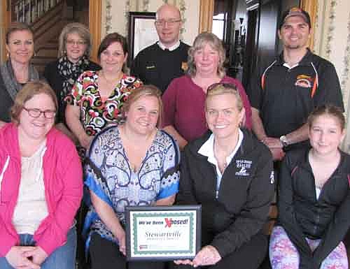 The Stewartville Area Chamber of Commerce celebrated its first-ever Business Xposed! event at the Stewartville Heritage House last week. Lori Miller-Beach, owner of the Heritage House, seated second from left, accepts a "Business Xposed" plaque from Beth Schmidt of the Chamber's Shop Local Committee. Others seated in front include Gwen Ravenhorst, Chamber administrator, left; and Maggie Beach, Lori Miller-Beach's daughter. Back row, from left, are Chamber members Chris Dahle, Stacey Schimmel, Jen Hruska and Robert Hruska; Laurie Wildeman of the Heritage House; and Joe Lawler, Chamber member.