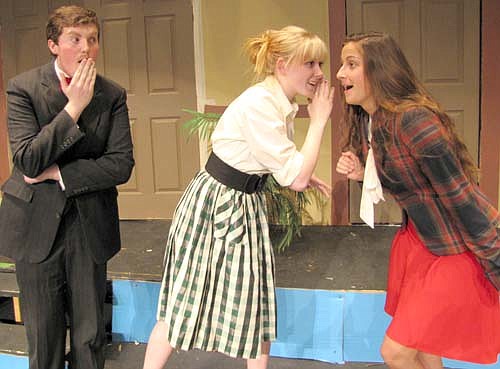 Mr. Dunlap (Nathan Lange) looks on as Miss Pippet (Kaylyn Hildebrandt), in the checkered dress, whispers "secrets" about her boss Claudia McFadden to nosy gossip columnist Dora Del Rio (Adrianna Nelsen-Gross) in a dress rehearsal for the Stewartville High School production of Suite Surrender, a classic farce to be presented at the Performing Arts Center this Friday, Saturday and Sunday.