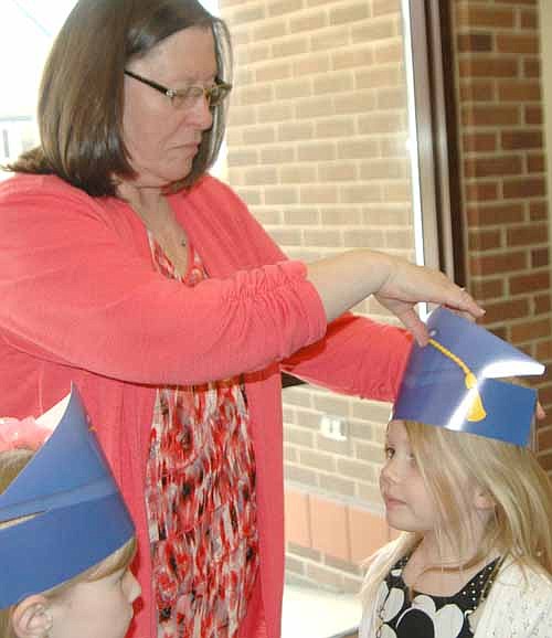 Barb Howes, director of Wee Care, places a  hat on graduate Keely Hinkle's head at the annual Wee Care graduation ceremony at St. John's Lutheran Church on Sunday, May 4. 