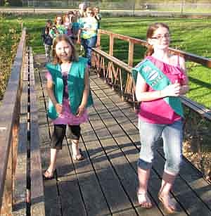 Kailah Weltzin of Troop 44037, left, bridged and flew up from Brownie to Junior in Girl Scouts as  Jalynn Colligan of Troop 43252, right, welcomes her across the bridge at Meadow Park in Stewartville last week. The bridging ceremony is part of Stewartville Girl Scouts' end-of-the-year awards ceremony.  The goal of this event, beginning and ending with a flag ceremony, is to honor the girls for their progression and growth.  Girls advancing a level cross the bridge to new adventures and responsibilities.  As part of the celebration, girls also performed a skit or song for the large audience that attended.