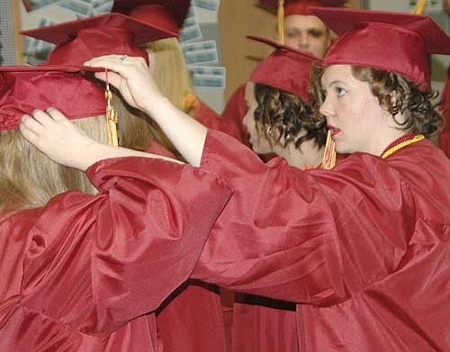 About 112 members of the Stewartville High School class of 2014 received their diplomas at the annual commencement ceremony at the SHS gym last Friday evening, June 6. Here,  Anna Erath, left, and Mikayla Engel, right, work to adjust Erath's mortarboard to prepare for the ceremony.