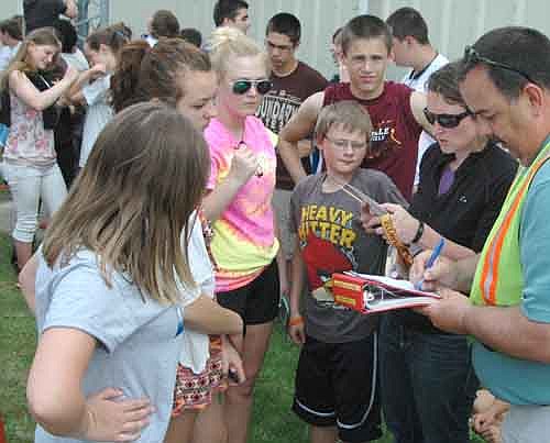 Dan Simmons, special education teacher, far right, checks attendance as students gather at the Grisim School Bus Inc. property after a practice evacuation of Stewartville High School/Middle School on Friday, May 30.