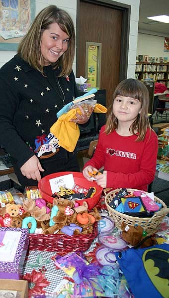 CHRISTMAS SHOPPERS -- Lindsay Smith, a kindergarten teacher at Bonner Elementary School, left, helps kindergartner Annabelle Jorgensen search for gifts at the school's BACPAC Santa Shop on Thursday, Dec. 20. BACPAC volunteers use money raised from milk caps and box tops to purchase items for the Santa Shop. Students bring in more milk caps and box tops to purchase the items at the shop. BACPAC funds pay for school materials and activities such as field trips. 