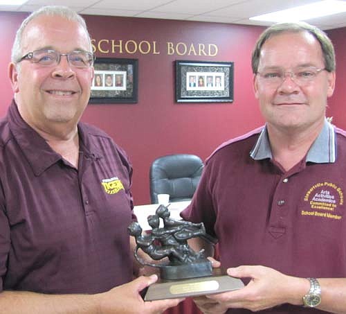 Bruce Hoff, left, who retired as principal of Stewartville High School effective June 30, accepts a trophy from Rob Mathias, chair of the Stewartville School Board, after last week's School Board meeting. Hoff worked in Stewartville schools for 19 years, including many as principal of SHS. "Thank you for all you've done," Mathias told Hoff.