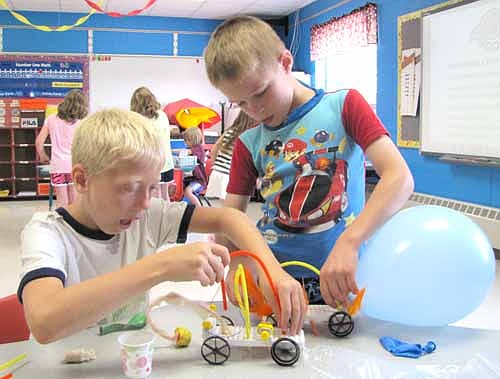Eight-year-olds Riley Schild, left, and David Watters, both of Stewartville, work on their cars at Camp Invention last week.