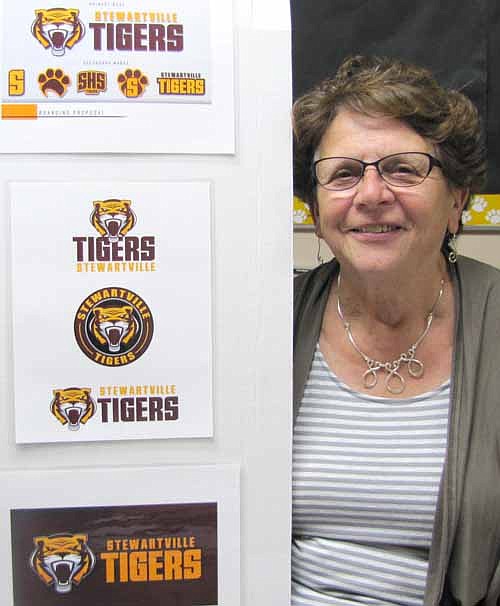 Sharon Morlock, athletic director, displays a few samples of the Stewartville School District's new official logo, which will be used on the district's Web site and will be placed on varsity football players' helmets.