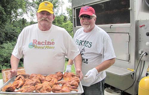 The Racine Lions Club hosted its annual chicken feed near the Racine Community Center on Saturday, July 19. Joe Dee of the Racine Lions, left, displays several of the 578 chicken halves that were cooked for the event. Bill Hurley of Parties Made Simple, right, cooked the chicken. Proceeds from the event will pay for Lions Club projects, Dee said.