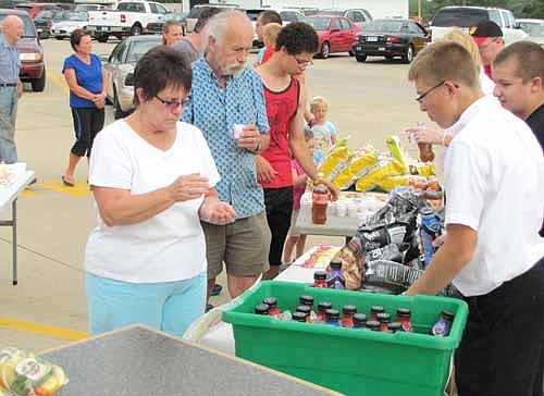 Derrick Fritz, near right, and Ben Zahradnik, second from right, Fareway employees, serve guests at The Dog Days of Summer event last Thursday, Aug. 21. Hundreds of Stewartville and area residents ate a variety of free hot dogs along with free chips, fruit, cookies, pretzels and drinks. Eight businesses from northeast Stewartville offered free food, includng Fareway, Bobcat of Rochester, Riverview Greens, the Trulson Dental Clinic, Advanced Body Chiropractic, Anytime Fitness, Active PT and Sports and First Farmers&Merchants State Bank.