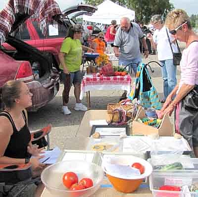 Lydia Hansen, 16, of rural Racine, sells a variety of items from her booth at the Stewartville Farmers Market last week. Sharon Peterson, right, inspects what's available.