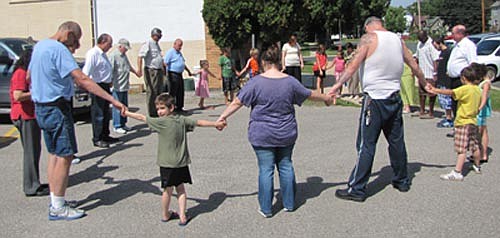 Members of Stewartville's Assembly of God Church hold hands in prayer before starting a prayer walk to Stewartville's schools on a hot and  humid Sunday afternoon, Aug. 24. Despite the heat, church members stopped at each local school to pray that students, teachers, staff members and administrators have a good year in 2014-15.