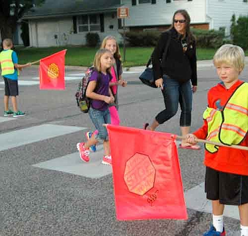 Students returned to Stewartville schools last Tuesday morning, Sept. 2. Here, Reed Neubauer, a third grader, right, keeps pedestrians safe as they cross a street near Bonner Elementary School.