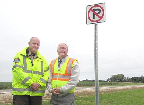 Zak Breitenbach, Stewartville's community oriented policing (COPS)&#8200;deputy, left, and Bill Schimmel Jr., city administrator, stand near a sign that tells people not to park along Tenth Street just north of Bear Cave Park.