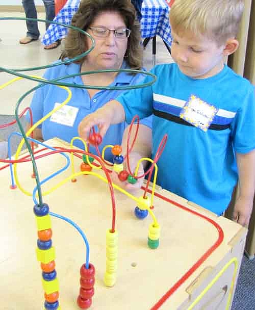 Lori Torgerson, Wee Care teacher, watches Logan Schlichter, 3, enjoy a game during the Wee Care Open House on Sunday, Sept. 7.