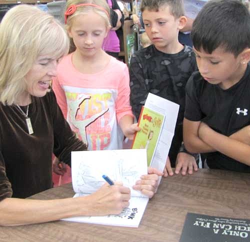 Alison McGhee signs copies of her books as students from Bonner Elementary School look on on Thursday, Sept. 11. McGhee read from her book, Countdown to Kindergarten, and shared insights about the writing process.