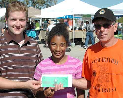 Bryan Young, left, and his daughter Malaika, 12, of Racine, were the grand champions of the annual grape-stomping contest at the Stewartville Morning Lions Club Fall Festival on Saturday, Sept. 20. Ernie Moeller of the Morning Lions presents the Youngs with the top prize, a total of $100 in Stewartville Bucks.