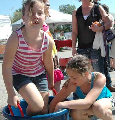Angela McClellan, 8, of Stewartville, grasps the bucket's handles as she crushes the grapes with her feet at the Stewartville Morning Lions Club's annual grape-stomping contest at the Stewartville American Legion Post 164 and Strikers Corner parking lots on Saturday, Sept. 20.