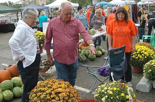 Gary and Patty Stensrud, left, inspect the mums at the Stewartville Morning Lions Club Fall Festival at the American Legion Post 164 and Strikers Corner parking lots on Saturday, Sept. 20. Linda Miller of the Morning Lions, right, stands ready to lend a helping hand. Hundreds of people attended this year's Festival, which moved from its previous location near downtown.