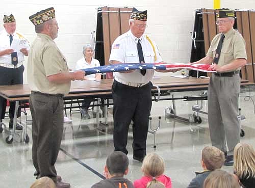 Four veterans and three members of the Stewartville Morning Lions Club shared patriotic lessons with the third graders at Bonner Elementary School on Constitution Day, last Wednesday, Sept. 17. The veterans, who demonstrated the proper way to fold an American flag, include, in front, from left, Roger Peterson, Wes Alrick and Tom Wacholtz. Dave Nystuen, another veteran in the background at left, describes to the students the meaning behind each fold. Nystuen, the former principal at Bonner, joined a medical unit in the Minnesota National Guard in 1967. Peterson, the commander of the Stewartville Prescher-Kumm VFW Post, served in Afghanistan nine years ago. Alrick was a military policeman for the U.S. Army during the Vietnam era, and Wacholtz was a paratrooper in Vietnam in 1968 and 1969. Del Jahns of the Morning Lions told the students that they should always respect the American flag. "It's important for us to know that the flag represents our freedom, and it represents all the men and women who fought for our freedom," she  said. Jahns and fellow Morning Lions Sharon Moehnke and Sheila Majerus brought dictionaries for the third graders. Jahns said that the dictionaries include all kinds of interesting information, such as the Declaration of Independence, the Constitution, maps of seven continents, information about the 50 states, weights and measures, and sign language.