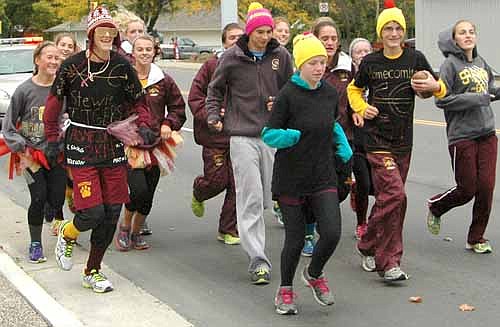 Members of the Stewartville High School cross country team run along Main Street in Stewartville as they carry the football game ball from Rochester Lourdes High School to the pre-homecoming pep rally at SHS on Friday, Oct. 3.