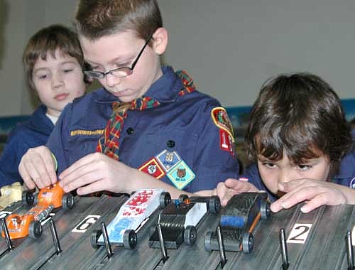 Webelos from Pack 156, Den 5, including Robert Feine, wearing glasses, left, and Ethan Schaefer adjust their cars for another trip down the track.