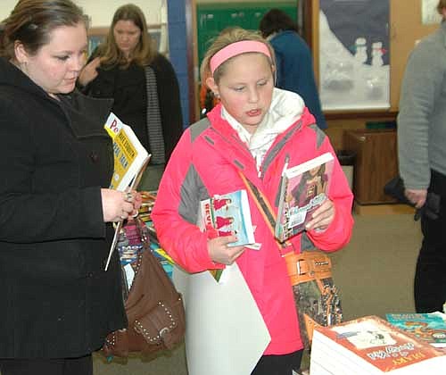 Kaylei Haley, a fifth grader at Central Intermediate School, right, browses among the books at the Central library during Literacy Night at the school on Friday, Jan. 30. Lucy Martin, Kaylei's stepmother, looks on at left. 