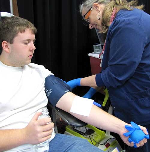Fredrick Flink, 16, a junior at Stewartville High School, is one of many students who gave blood at the Mayo Clinic Blood Drive at SHS on Wednesday, Feb. 4. Sue Broich of Stewartville, an LPN, assists Flink.