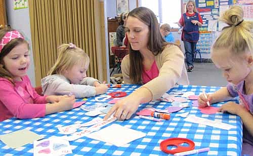 Holli Litrenta, a volunteer parent, helps students, clockwise from left, Emily House, Maddy Brown and Emma Rahlf with their valentine art projects at St. John's Lutheran Church's Wee Care on Thursday, Feb. 12. Litrenta's daughter Mya attends Wee Care. Kathy Dux, a Wee Care teacher, is in the background.
