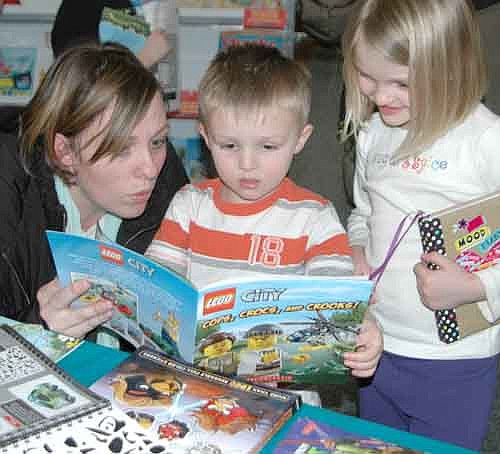 Kaysie Manion, a chemistry teacher at Stewartville High School, left, reads a Lego book, "Cops, Crocs and Crooks!" to her son Mason, 3, and daughter Morgyn, 6, at the second annual Read S'more Literacy Night at Bonner Elementary School on Friday evening, Feb. 27. In all, 672 Stewartville and area residents attended. Matt Phelps, Bonner's  principal, said that the event is designed to help families celebrate a love of literacy. "More reading makes for better readers," he said.