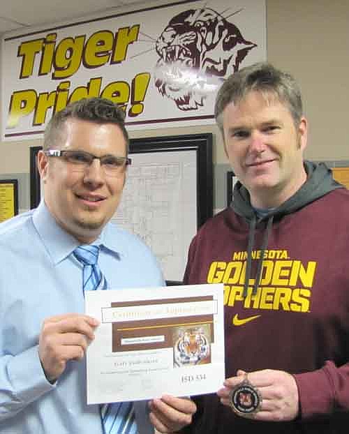 Scott Gulbranson, right, accepts a Tiger Token from Steve Gibbs, principal of Stewartville High School and Middle School.