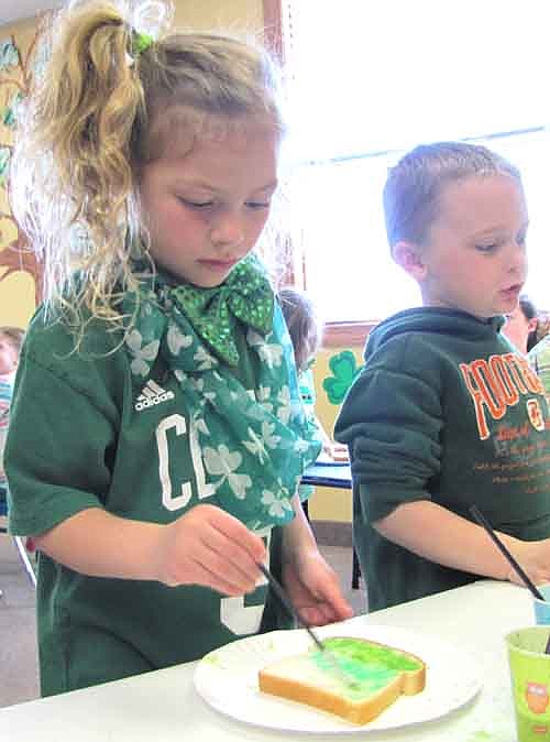 The pre-kindergarten 4- and 5-year-olds at Tiger Time Preschool ate green toast to celebrate St. Patrick's Day at Grace Evangelical Free Church last Tuesday, March 17. At left, Sydney Hedin, 5, of Rochester, applies the milk and green food coloring to her toast.