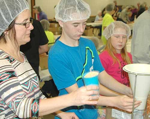 FOOD FOR THE POOR -- From left, Robin Sterzinger and her son Tanner, 14, of Ivanhoe, Minn., and Mesa Wibben, 10, a fifth grader at Central Intermediate School, work at the Food for Kidz food packaging event on April 11.