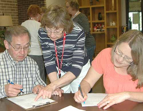 Mary Olson, standing, a member of the Stewartville Area Disaster Team,  helps Keith and Jane Johnson of Rochester register their names and information during a mock disaster drill at Zion Lutheran Church on Saturday, April 18. 
