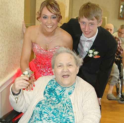 PROM AT THE CARE CENTER -- Taylor DeGeus, a senior at Stewartville High School, standing at left, and Anthony Schoeppner of Oronoco stopped by the Stewartville Care Center before heading off to SHS's prom on Saturday, April 18. DeGeus and Schoeppner said hello to a number of Care Center residents, including Anneliese Laske, seated. DeGeus knows many of the residents because she works in the activities department at the Care Center.