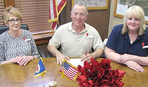 Mayor Jimmie-John King, center, recently signed a proclamation declaring May as "Poppy Month" in the city of Stewartville. Throughout this month, members of the Stewartville American Legion Auxiliary Unit 164 will offer poppies in exchange for  a donation to help veterans. The poppies will be available at the Stewartville American Legion Post 164. King's proclamation declares that the American Legion Auxiliary, the American Legion, the Veterans of Foreign Wars and the Veterans of Foreign Wars Auxiliary have adopted the poppy as their commemorative symbol. "The memorial poppy, assembled by disabled veterans, pays respectful tribute to those killed in war, and also benefits living veterans and their families," the proclamation states. "Public donations for poppies fund rehabilitation programs within each local community that benefit veterans, their families and ultimately our state and nation." Flanking Mayor King are Wanda Prescher, president of the American Legion Auxiliary, left; and Laurel Jacobs, a member of the Auxiliary Executive Board.