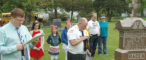 Jeremiah Oeltjen of the Sons of the American Legion, left, prays during a ceremony at St. Bernard's Catholic Cemetery on Memorial Day morning. Thom Blade, Legion commander, stands at center in the foreground.